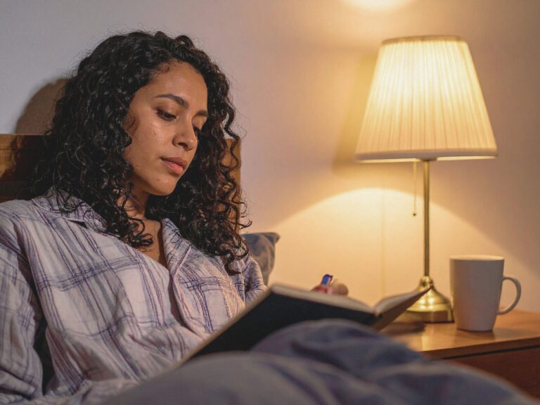 Woman journaling in her bed while healing from feeling like a failure after divorce.